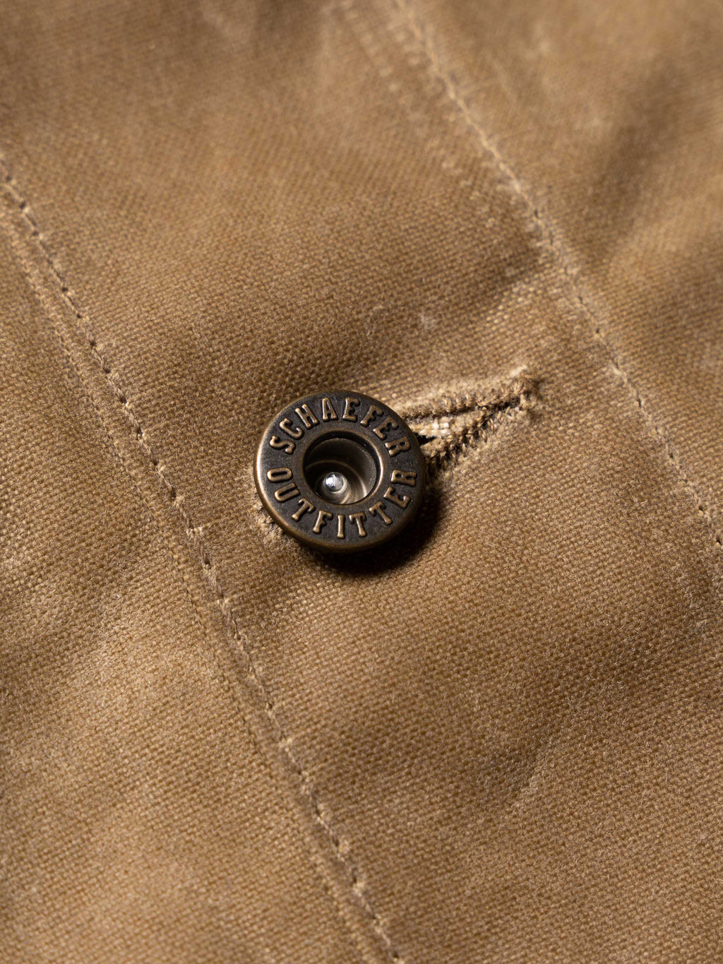 RangeWax® Mesquite brush jacket snap detail with brand button on sand fabric